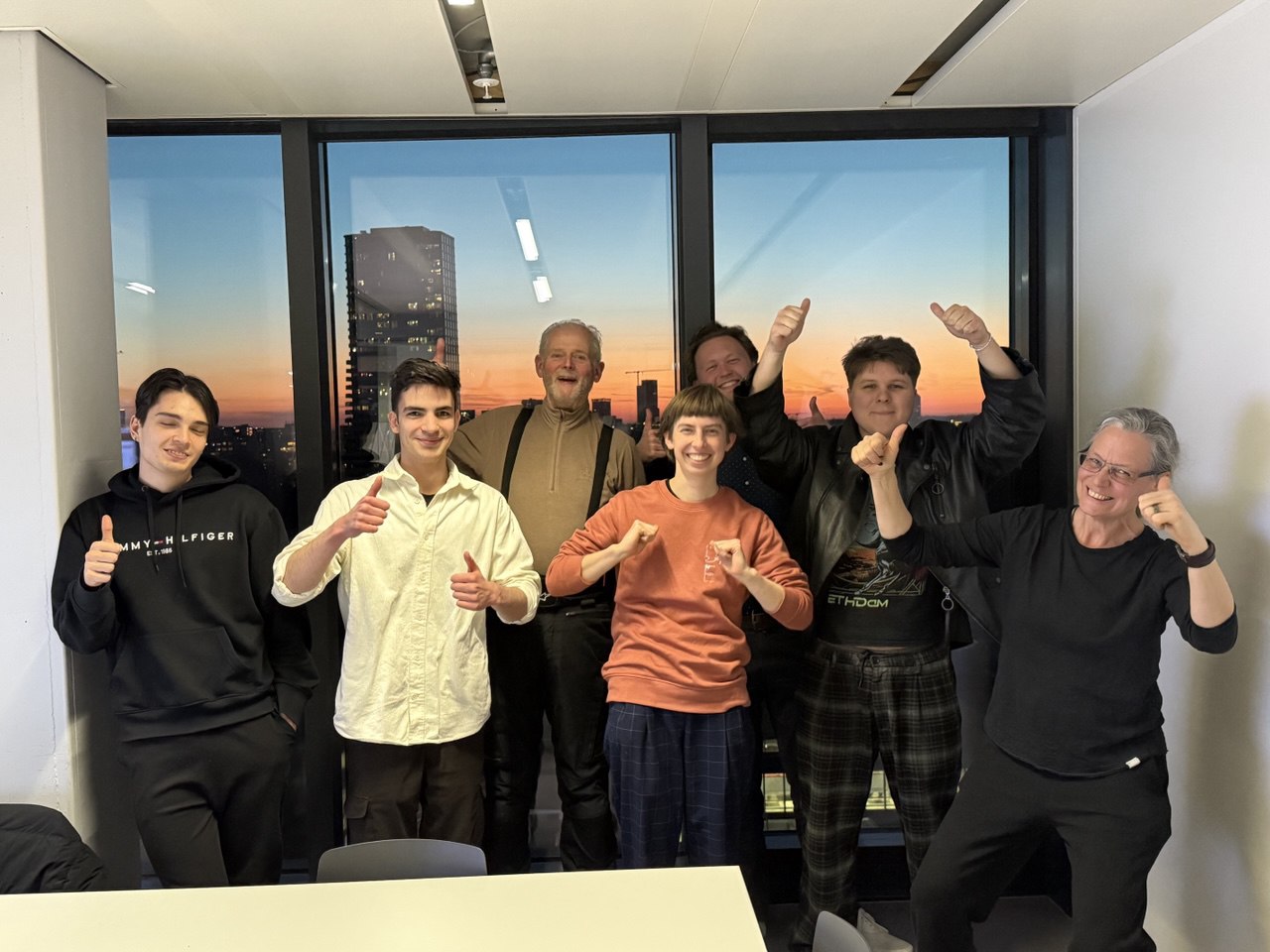 Participants of the 2025 Introduction Fellowship giving a thumbs up in front of a sunset window